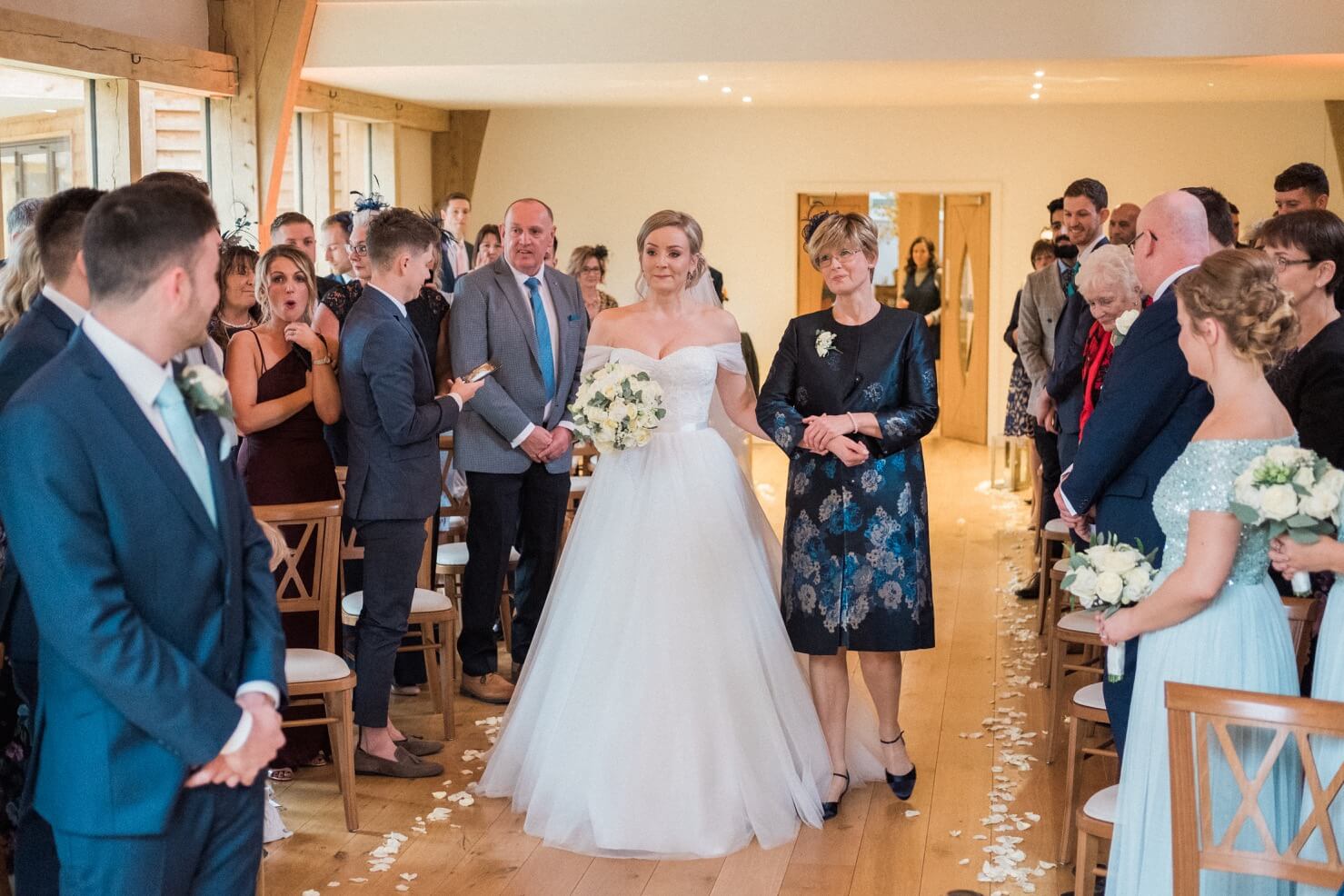 Tearful bride walking down the aisle with her mum