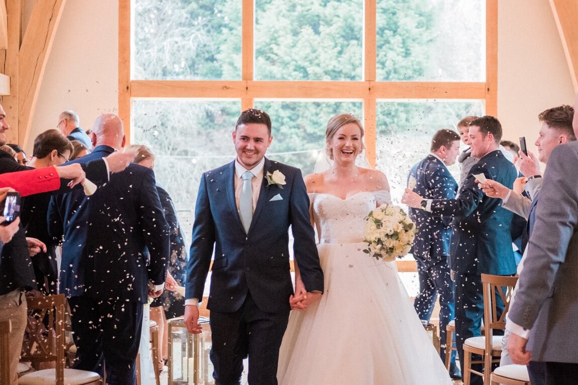 Confetti as the newlyweds leave the ceremony barn