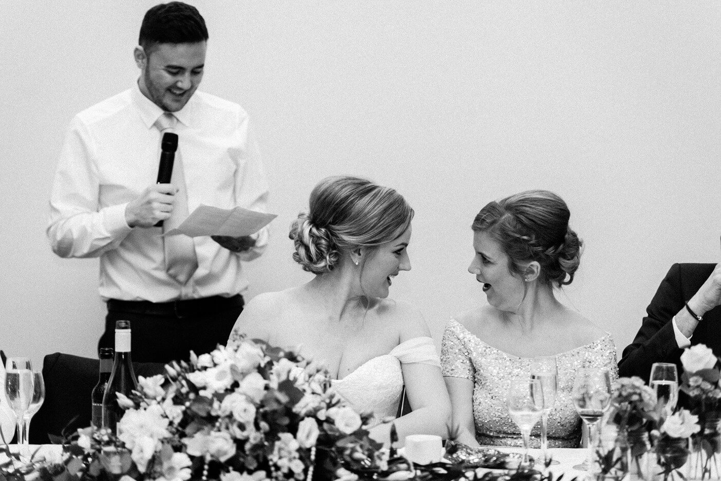 Bride and bridesmaid reacting during the speeches