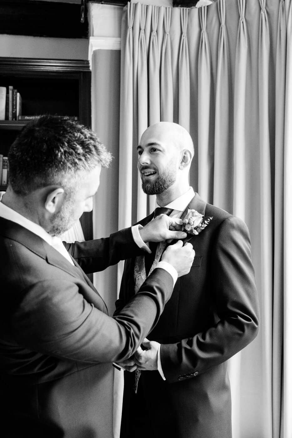 Groomsmen helping the groom with his buttonhole