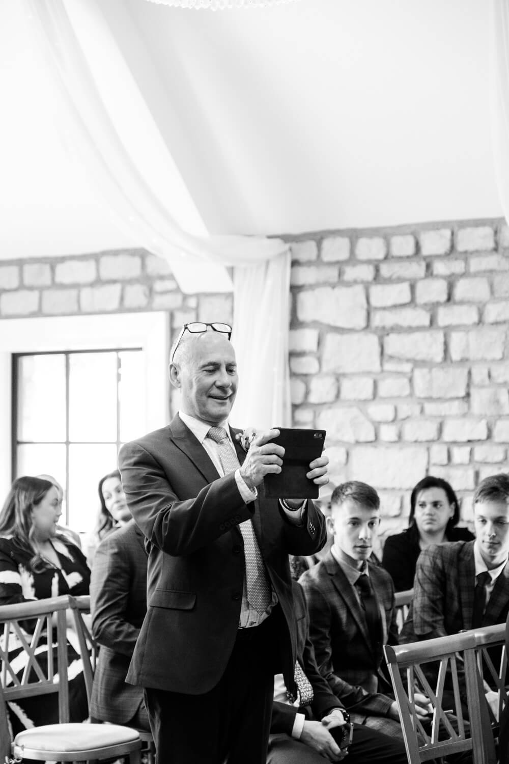 Wedding guest taking a photo during the ceremony at The Pear Tree Purton