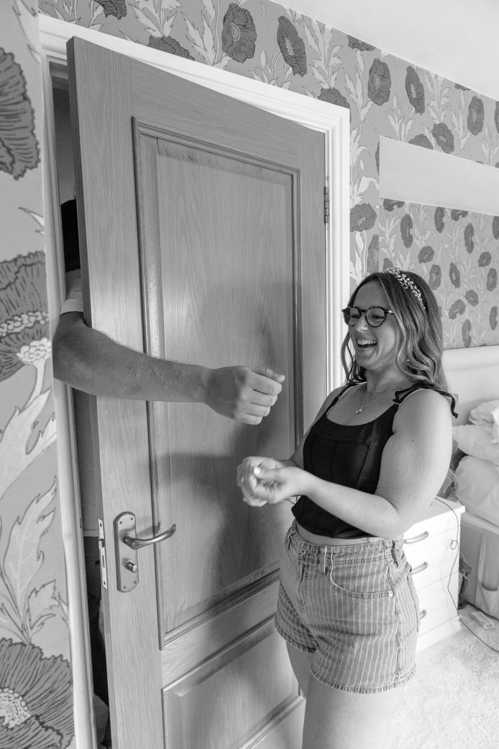 The groom's arm through the door as the bride reaches to tie on a band