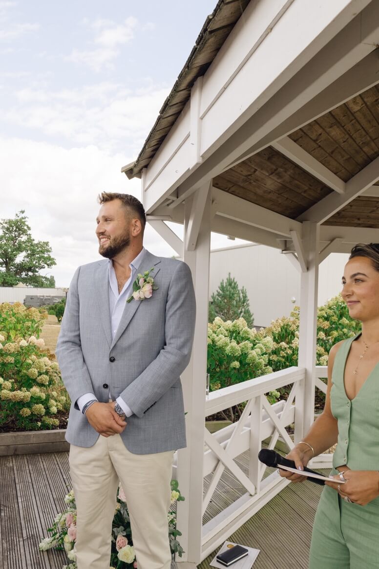 The groom smiling as he sees the bride