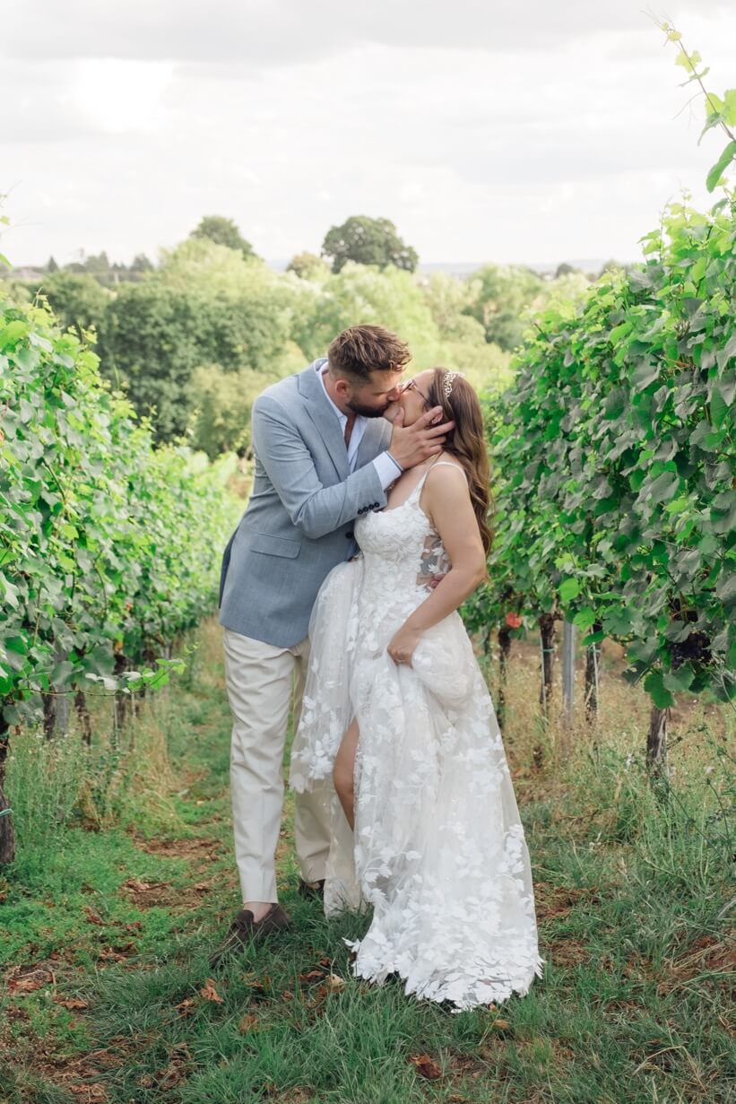 The couple sharing a kiss among the vines